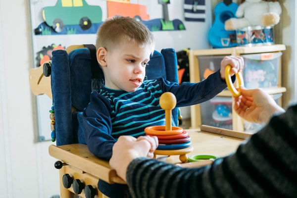 child with Angelman syndrome learning to play in a preschool