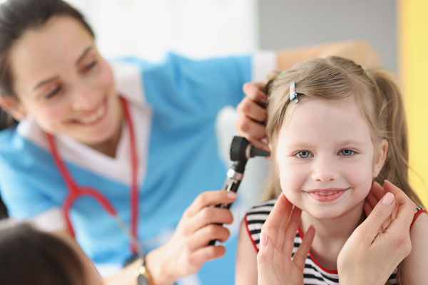young child's ear being examined by a doctor to assess for hearing impairment