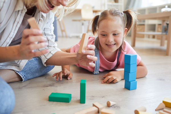 small child with down syndrome playing with building blocks