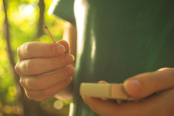person holding matches in a forest