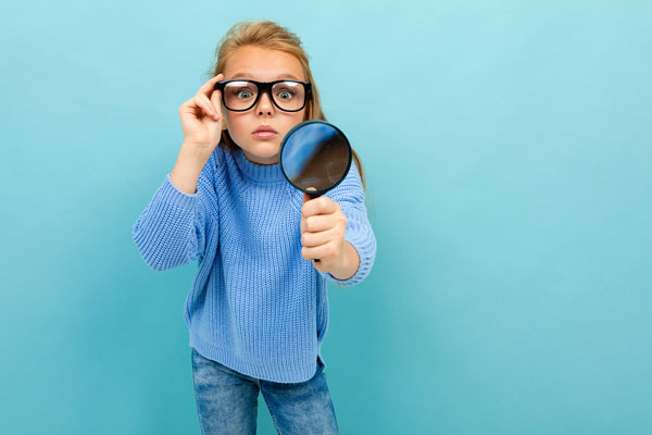 Young girl wearing glasses and using a magnifying glass because of her vision impairment