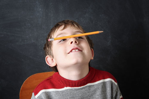 Small boy balancing a pencil on his nose at school