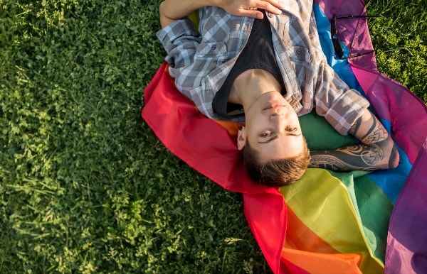 homosexual laying on the grass with a pride flag