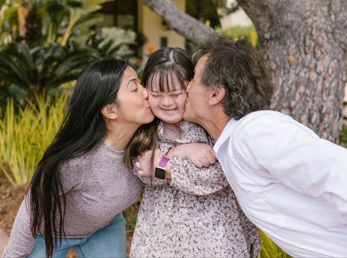 Two adults supporting an autistic child