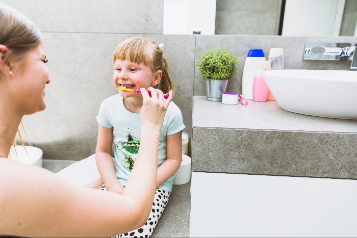 child brushing teeth with parent