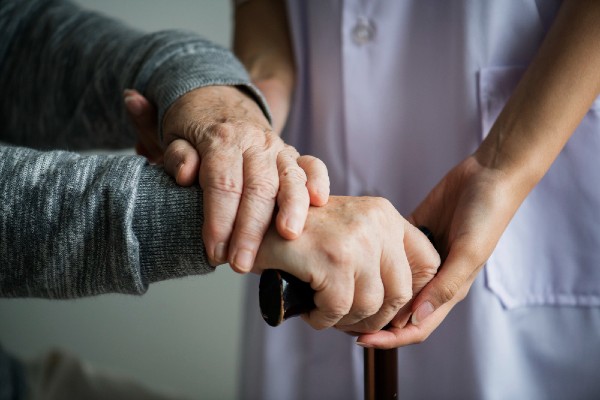 close up of a carer holding hands of a disabled person