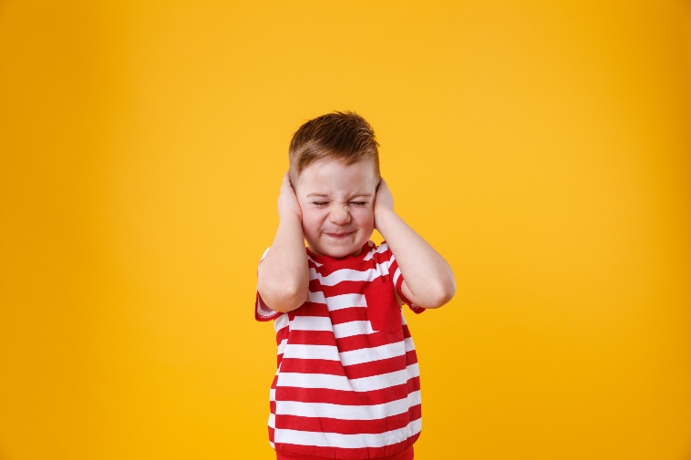 Little boy is distressed by loud noise because he has sensory processing disorder so he covers his ears