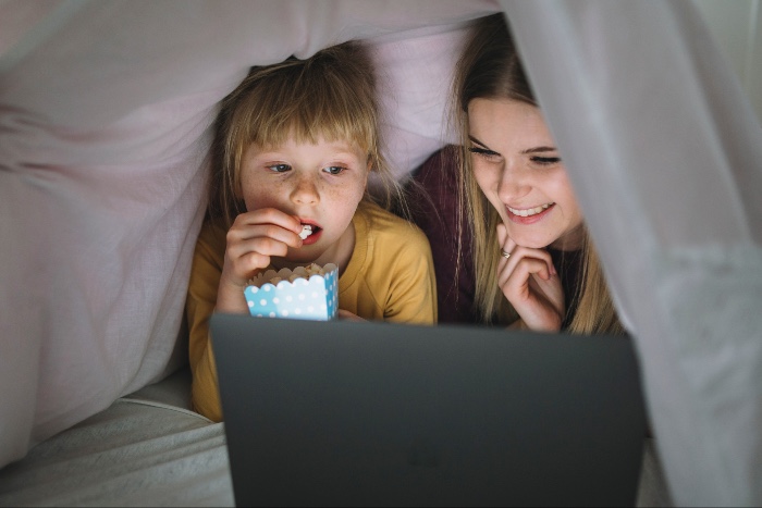 children watching a screen under the bed sheets