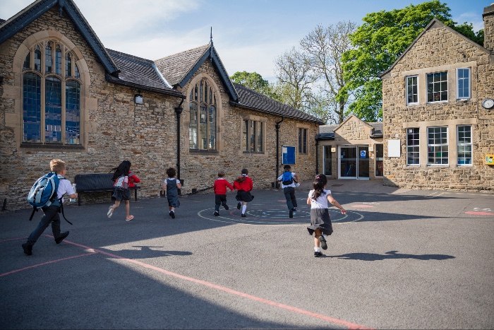 photograph of children running across the playground of their school in England