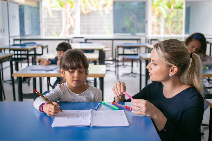 teacher assisting a young pupil at school with SEN